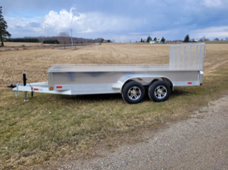 Silver utility trailer with two tires, parked on gravel.