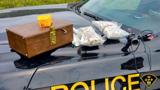 Brown wooden chest and a bag of white powder on a car hood
