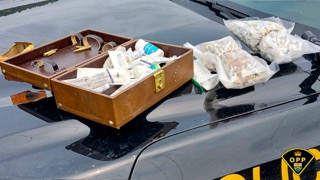 Vintage suitcase filled with syringes and baggies of a white substance.