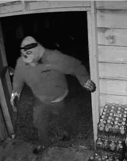 Person wearing a mask and dark clothing, blurred motion.