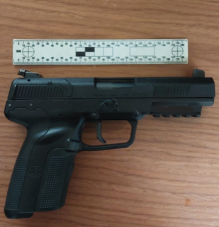 Black handgun on a ruler