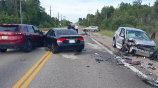 Three cars involved in a collision on a two-lane road. Debris scattered across the pavement.