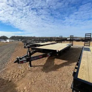 Several black utility trailers on a dirt lot