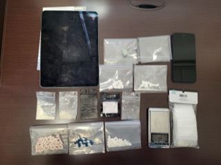 Several small plastic bags containing white pills and a small amount of white powder. Digital scale.