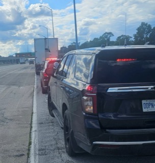 Two SUVs, one black and one red, are stopped in traffic on a highway.