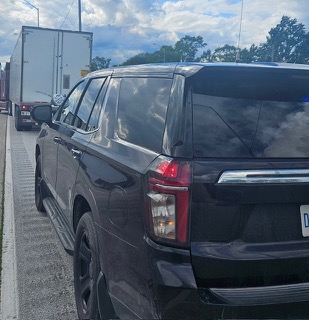 Black Ford Explorer parked alongside a semi-truck.