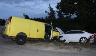 Yellow van and white sedan collided, significant damage to both vehicles.
