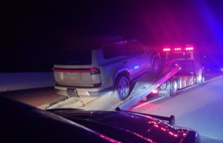 White SUV on a car trailer, blue and red lights
