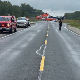 Helicopter and emergency vehicles on a wet road.