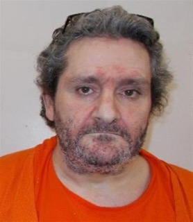 Man with dark, curly hair and a full beard, wearing an orange shirt.