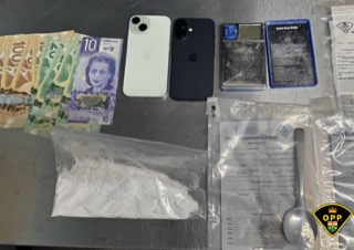 Canadian twenty and ten dollar bills, a white iPhone, a baggie with a white powdery substance, a small baggie with a brown leafy substance, a document, and a spoon.