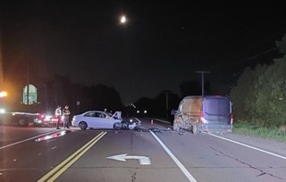 Two vehicles collided on a dark road. Debris is scattered across the pavement.