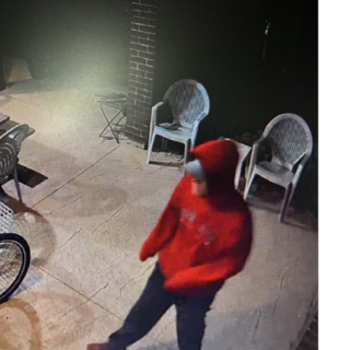 Person in a red hoodie walking past two chairs