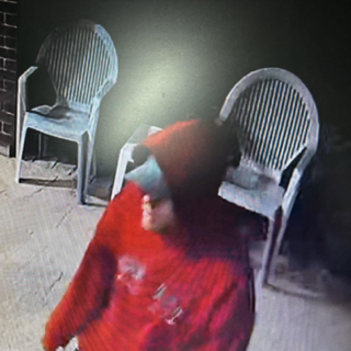 Person in a red hoodie, partially obscured by a chair.