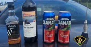 Wisers Deluxe whiskey bottle, dark rum bottle with a horse illustration, two cans of Clamato juice, OPP logo