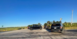 Black pickup truck and SUV stopped on a rural road