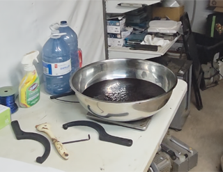 Silver pan filled with dark liquid on a scale.