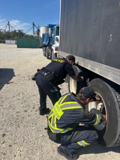 Two officers inspecting a semi-truck tire