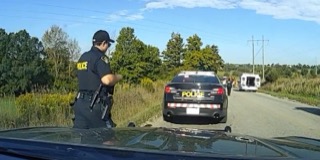 Police officer standing near a police car, roadside scene