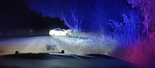 Damaged white car off a road, police lights