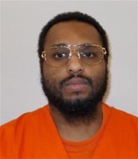 Man wearing orange shirt and gold-rimmed glasses, dark beard