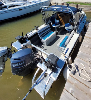 Aluminum fishing boat with two outboard motors, docked on a wooden pier