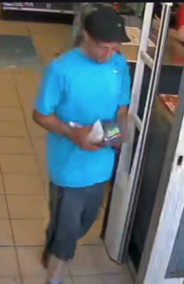 Person in blue shirt and black shorts holding a small bag