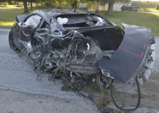 Heavily damaged black car on asphalt.