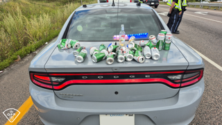 Several cans of beer in the trunk of a police car.