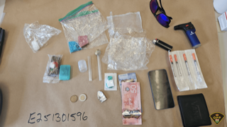 Small baggies, pills, a pipe, Canadian twenty and fifty dollar bills, sunglasses, a lighter, a phone, and a document on a surface.