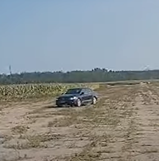 Black car driving on a dirt road.