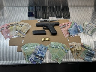 Canadian currency and a handgun on a black surface.