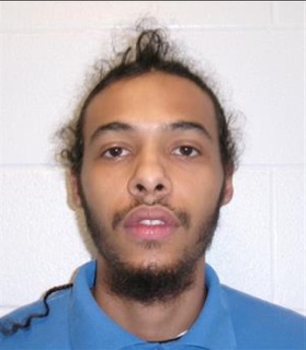 Man with short, curly dark hair and beard, wearing a blue polo shirt.