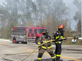 Two firefighters hose a brush fire.