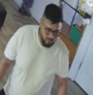 Man with short hair and glasses, wearing a white t-shirt