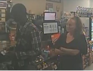 Two people talking in a store with shelves of merchandise.