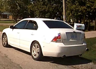 White sedan parked on a gravel driveway