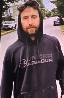 Man with dark hoodie, visible facial hair