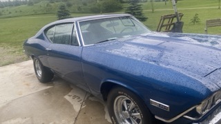 Dark blue classic car, wet, on a concrete driveway