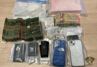 Stacks of Canadian twenty-dollar bills and several smartphones in cases.