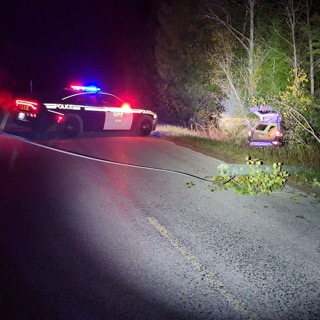 Police vehicle with flashing lights, damaged vehicle off the road