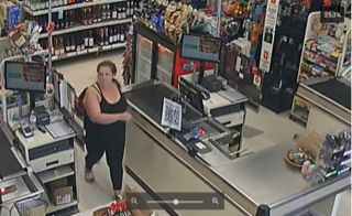 Person in black tank top and leggings stands in a convenience store.