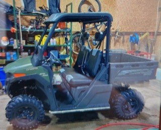 Green utility vehicle with black tires and a cargo bed.
