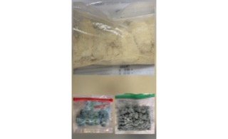 Two clear plastic bags of a green leafy substance and a bag of dark gray rocks.