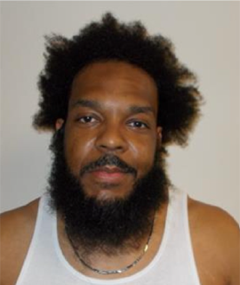Man with a full beard and afro, wearing a white tank top