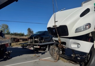 White tow truck with damaged front end.