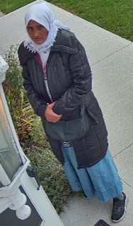 Person in black coat and blue skirt, wearing a white headscarf