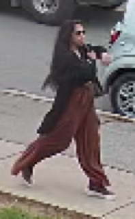 Person walking, wearing black top and maroon pants
