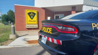 Police cruiser parked in front of a building, &quot;POLICE&quot; displayed on the vehicle, license plate visible