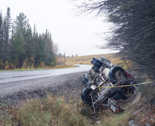Semi-truck trailer overturned on roadside, yellow caution tape visible
